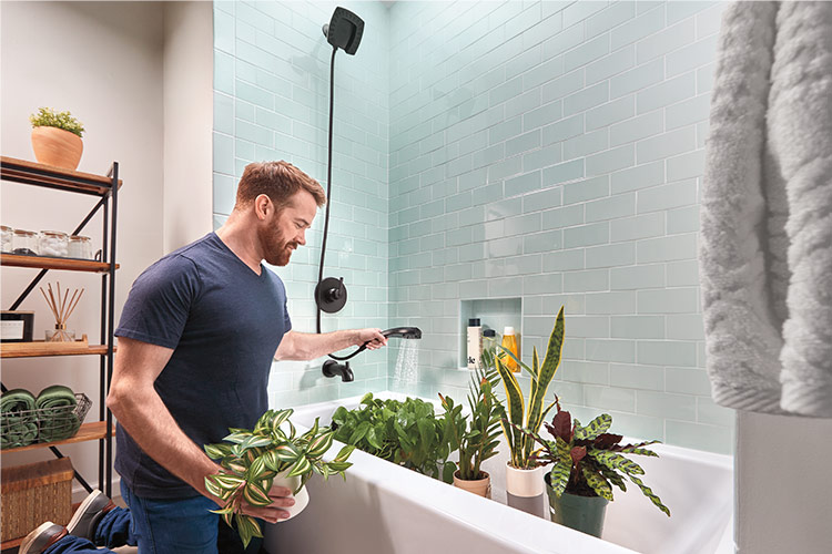 hombre regando las plantas en la bañera usando un cabezal de ducha dos en uno